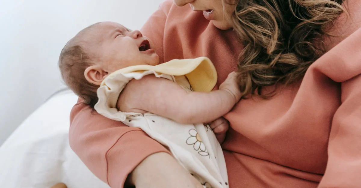 Mãe acalmando o bebê que chora no colo