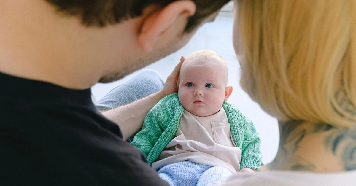 Criança observando os pais com o bebê recém-nascido no colo