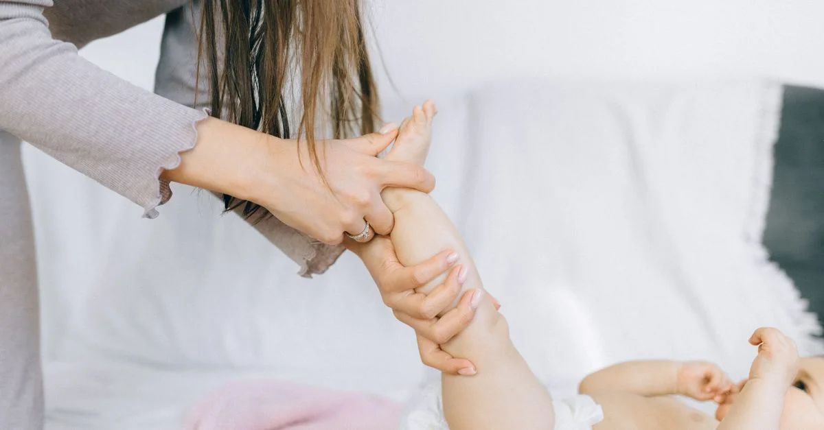 Mãe massageando a barriga do bebê para aliviar cólica