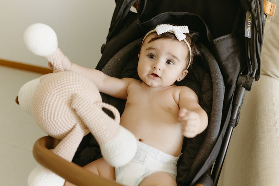 Bebê deitado em carrinho de bebê segurando um boneco de pelúcia, com expressão curiosa.