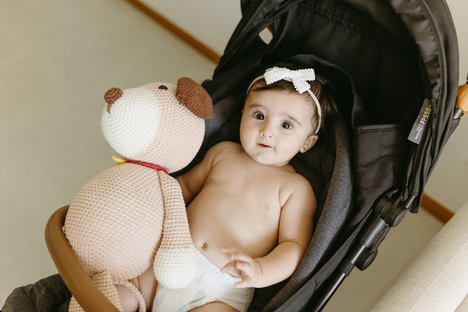 Bebê sorridente sentado em carrinho de passeio segurando um brinquedo de pelúcia.