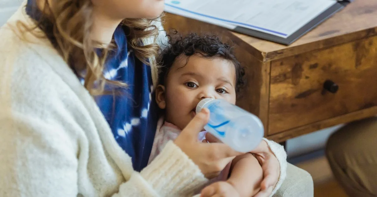 Mãe alimentando o bebê com mamadeira no colo
