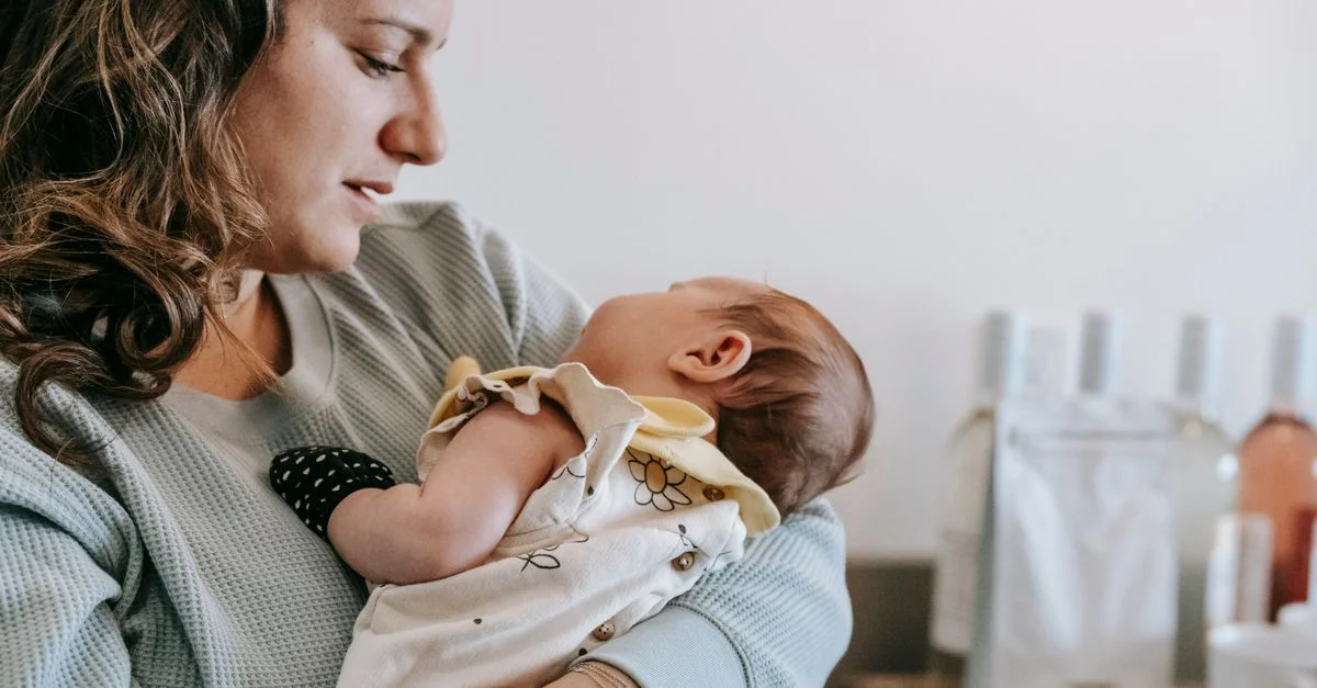 Mãe segurando o bebê no colo sozinha em casa