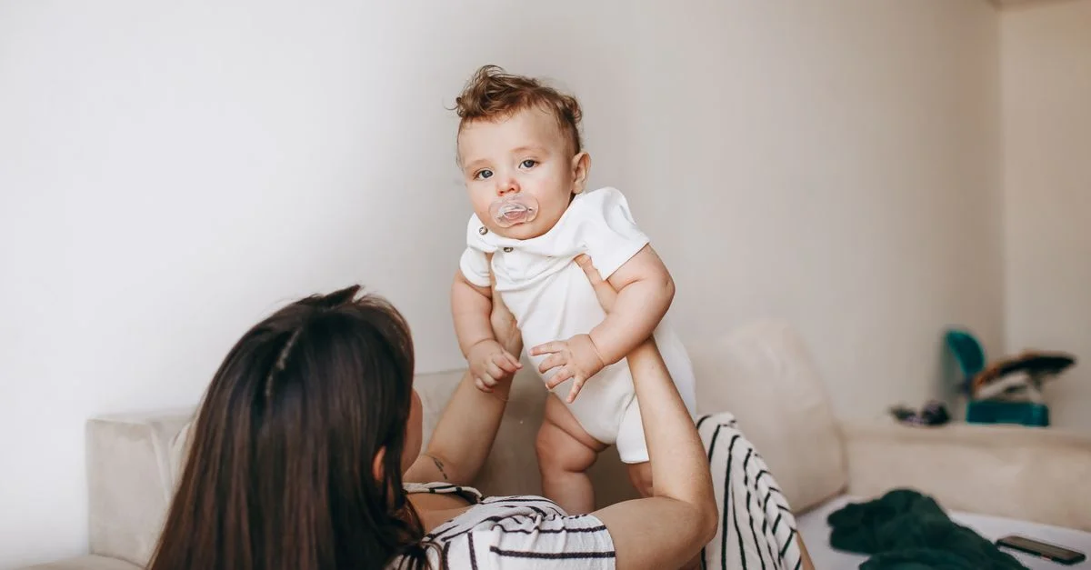 Mãe organizando roupinhas de bebê menino no quarto