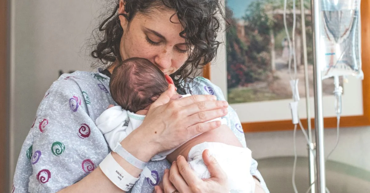 Mãe exausta segurando o recém-nascido logo após o parto