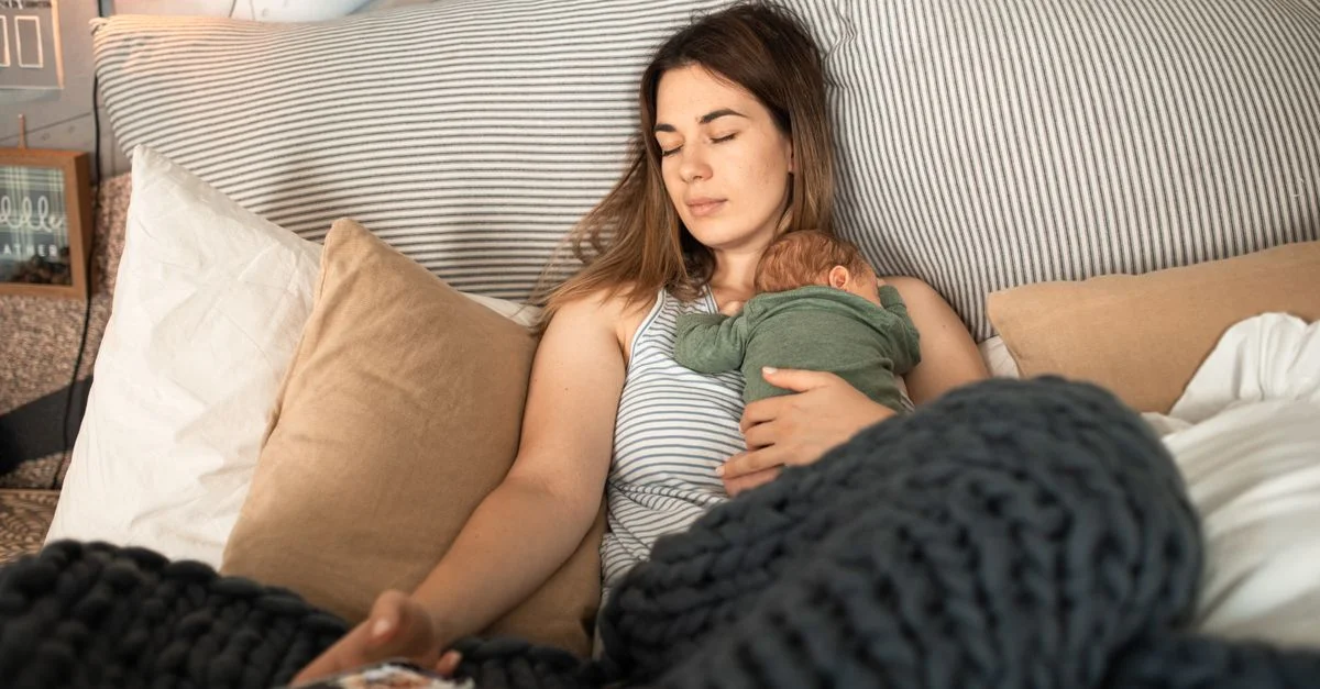 Mãe descansando de olhos fechados enquanto segura o bebê
